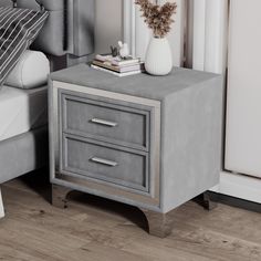 a nightstand with two drawers and a vase on it next to a bed in a bedroom