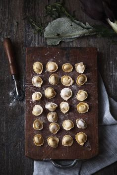 a wooden cutting board topped with small pieces of food next to a knife and flowers