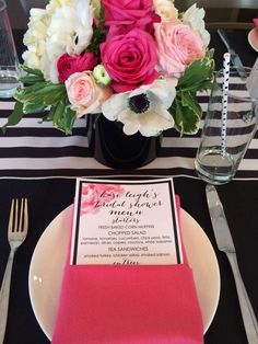 pink and white flowers are in a vase on a table with black and white stripes