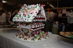 a large gingerbread house with icing and candy on it's roof at a christmas party