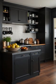 a kitchen with black cabinets and wooden floors is pictured in this image, there are lemons on the counter