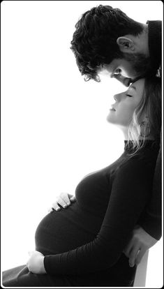 a pregnant woman and man standing next to each other