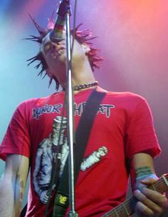 a man with dreadlocks on his head playing an electric guitar in front of a microphone