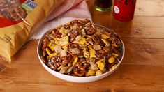 a bowl filled with cereal and nuts next to a bag of cheesy crackers