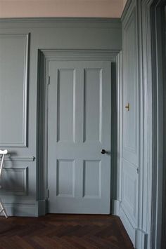 an empty chair sits in front of the door to a room with gray walls and wood floors