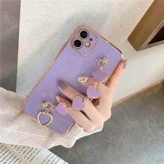 a woman holding up her phone case with two heart shaped charms on the front and back