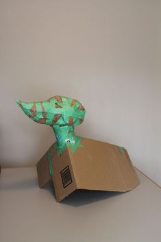 an origami dinosaur head sitting on top of a cardboard box