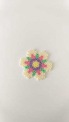 a white surface with a flower made out of beads