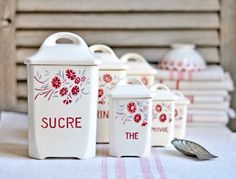 a table topped with white canisters filled with red flowers and the words sucre