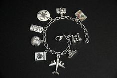 "A collection of silver plated travel and tourism themed charms have been dispersed around a shimmering silver plated bracelet chain in this handmade charm bracelet. This world traveler charm bracelet is then completed with a lobster clasp and a 1/2 inch of chain at the end for adjustable sizing. Charms in this bracelet include an airplane charm, passport charm, \"find joy in the journey\" charm, world charm, camera charm, \"bon voyage\" charm, suitcase charm, binoculars charm, and compass charm Travel Sterling Silver Jewelry, Silver Metal Jewelry For Travel, Nickel-free Silver Bracelets As Souvenir, Silver Nickel-free Bracelet Souvenir, Adjustable Silver Jewelry For Travel, Camera Charm, Find Joy In The Journey, Travel Bracelet, Handmade Charm Bracelets