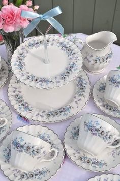 a table topped with lots of white and blue dishes next to pink carnations