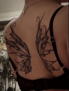 the back of a woman's bra with butterfly tattoos on her upper and lower back