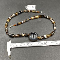 A beautiful Luk Mik Bead with rare shape and natural Pattern with natural Line in the center of Necklace along with 12 century khmer Angkor Empire Banded Agate Beads Luk mik means in Tibet (Goat's eye) or Ta Mik (horse eye) The beads got very shinny and smooth surface because of long passage of time using in necklaces and in prayers mala The agate beads were used in ancient times by rich Noble people of that time some orange color carnelian beads are used in necklace as spacers we provide fast a Onyx Gemstone Beaded Necklace, Onyx Gemstone Beaded Necklaces, Round Faceted Agate Beads, Faceted Agate Beads, Polished Onyx Beaded Necklaces, Hand-strung Onyx Beaded Necklaces With Round Beads, Hand-strung Onyx Beaded Necklace With Round Beads, Onyx Beaded Necklaces With Polished Round Beads, Faceted Bead Agate Necklace