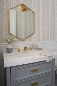 a bathroom sink with a mirror above it and a vase on the counter next to it