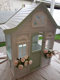 a doll house with flowers in the windows and doors on it's sides, sitting on a table