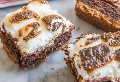 several pieces of brownie with white frosting and chocolate toppings sitting on a marble surface