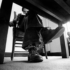 a person sitting at a table with their feet up on a chair and holding a cell phone