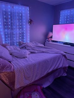 an unmade bed in a bedroom with blue lights on the windows and curtains behind it