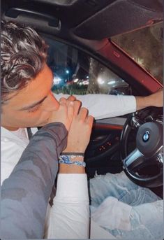 a man sitting in the driver's seat of a car with his hands clasped