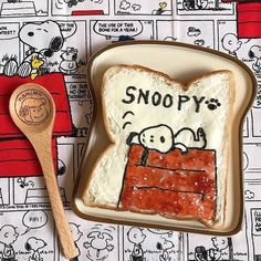 a peanut butter and jelly sandwich with snoopy written on it next to a spoon