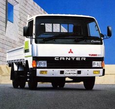 a white truck is parked in front of a building with a blue sky behind it