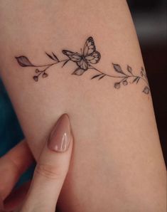 a woman's arm with a butterfly and flower tattoo on the left side of her arm