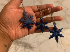 a hand holding three blue snowflakes on it's fingers, with one being held in the air