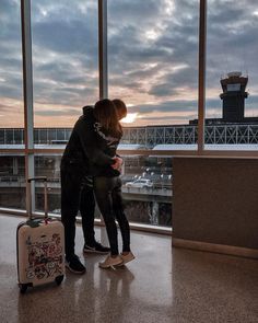 two people standing next to each other in front of large windows with an airport control tower in the background