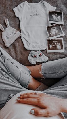 a person laying on top of a bed next to baby clothes and pictures with babies in them