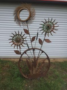 metal sunflowers in a wheel on the grass near a building with a door