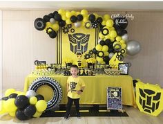 a young boy standing in front of a table with yellow and black decorations