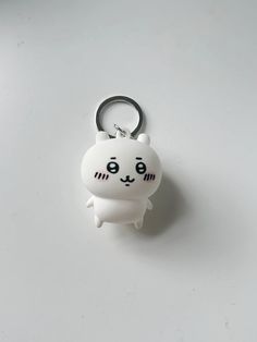 a white cat keychain sitting on top of a white table next to a bottle opener