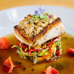 a white plate topped with food and garnishes on top of broth