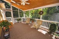 an enclosed porch with chairs and potted plants