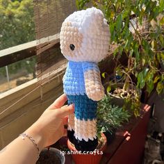 a crocheted teddy bear in a blue and white shirt sitting on top of a potted plant