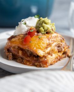 a white plate topped with lasagna covered in cheese and guacamole