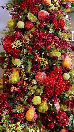 a christmas tree decorated with red and green balls, pomegranates, pine cones, berries and other holiday decorations