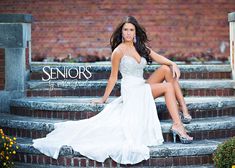 a woman in a white dress is sitting on some steps and posing for the camera