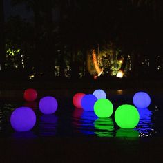 glowing balls are floating in the water at night