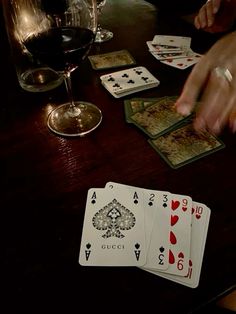 a table with playing cards and a glass of wine