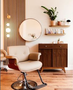 a white chair sitting in front of a mirror on top of a wooden cabinet next to a shelf