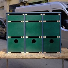 four green boxes sitting on top of a wooden table in front of a white van