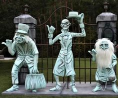 three statues of people dressed as witches and wizard's in front of a gate