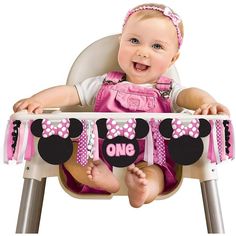 a baby sitting in a high chair with minnie mouse decorations