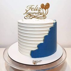 a white and blue cake with gold lettering on top is sitting on a silver platter