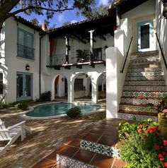 a house with a pool in the front yard and stairs leading up to it's second story