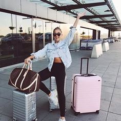 a woman is posing with her luggage at the airport