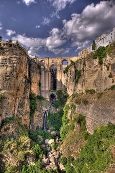 an old bridge is built into the side of a cliff with a waterfall running down it