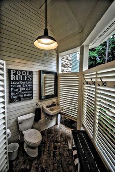 a bathroom with a toilet, sink and window covered in slatted shutters