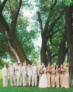 a group of people standing next to each other in front of some trees and grass